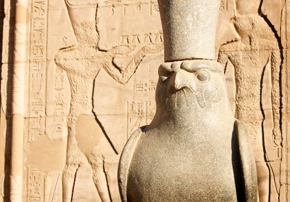statue of egyptian god horus with hieroglyph wall