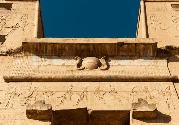 high wall front facade of Egyptian Edfu Temple of falcon god Horus, with carving figures and hieroglyphs, in Egypt, Africa